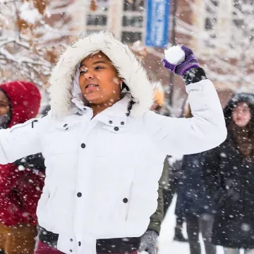 在一个下雪天的打雪仗中，一名学生在打雪仗中向后转去扔雪球